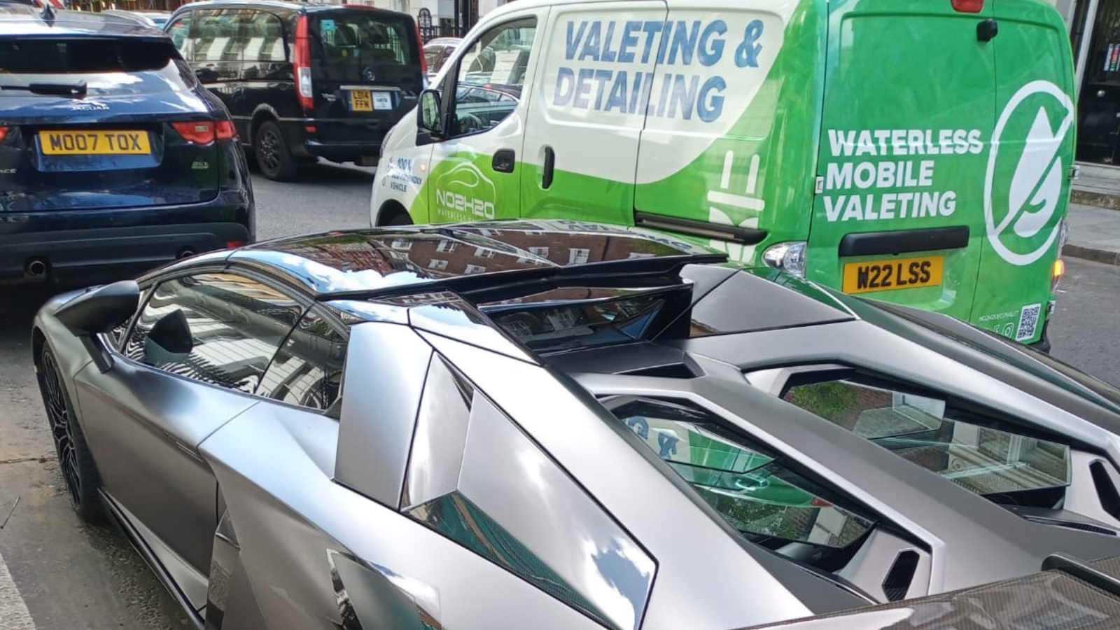 Matte silver Lamborghini Aventador beside the NO2H2O waterless mobile valeting van in central London